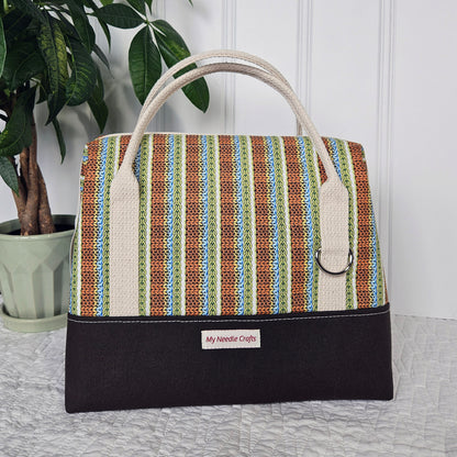 Doctor style knitting bag has brown canvas bottom paired with an orange blue green knit stitch print top. It has natural cream cotton webbing strap handles.